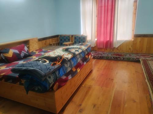 a bedroom with a bed in a room with wooden floors at Manepa Homestay Kardang in Kyelang