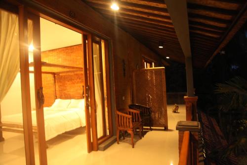 a bedroom with a bed and a sliding glass door at Ubud Suites Batuan in Sukawati