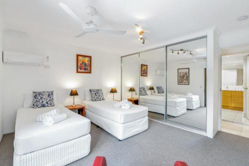 a living room with two white beds and a mirror at Argosy On The Beach in Clifton Beach