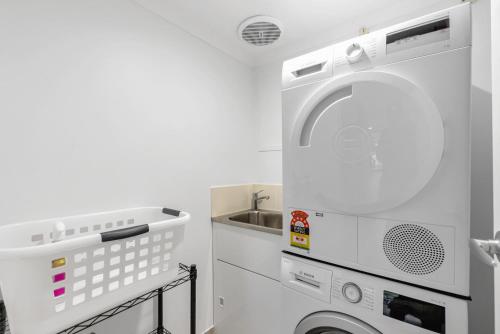 a kitchen with a washing machine and a sink at Argosy On The Beach in Clifton Beach