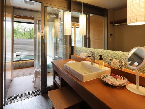 a bathroom with a sink and a mirror and a tub at Bettei Wankobiyori in Ashikita