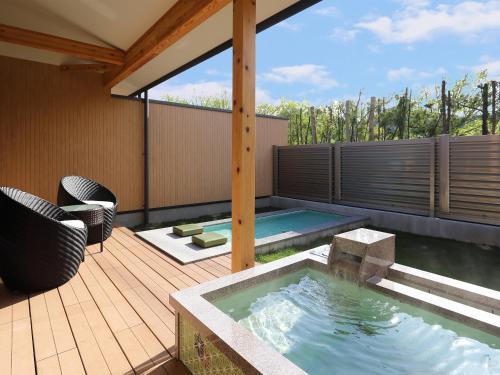 a hot tub on a wooden deck with a patio at Bettei Wankobiyori in Ashikita