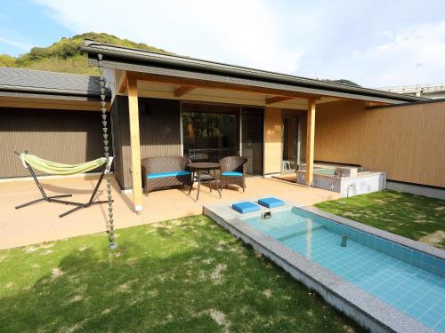 a patio with a hammock and a pool at Bettei Wankobiyori in Ashikita
