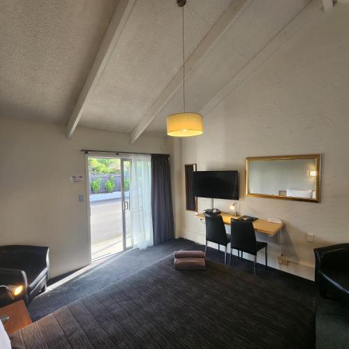 a room with a desk and chairs and a television at 16 Northgate Motor Lodge in New Plymouth