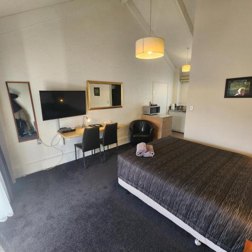 a room with a bed and a desk and a computer at 16 Northgate Motor Lodge in New Plymouth