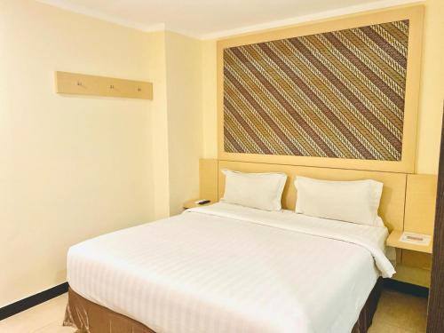 a white bed in a room with a large window at Jakarta City Hotel in Jakarta