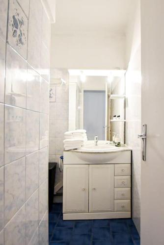 une salle de bain blanche avec un lavabo et un miroir dans l'établissement Appartement T3 parking à 5 minutes a pied du stade vélodrome, à Marseille