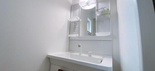 a white bathroom with a sink and a mirror at 夢富良野 in Furano