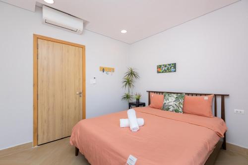 - une chambre avec un lit avec des draps orange et une porte dans l'établissement ARIA Vũng Tàu - Thành Phố Vũng Tàu, à Xã Thắng Nhứt