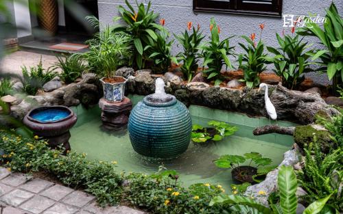a garden with a pond with vases and plants at 5H Garden in Ho Chi Minh City