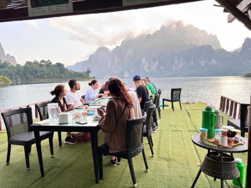 a group of people sitting at tables near the water at Amornkeeree Khao Sok Camping in Khao Sok