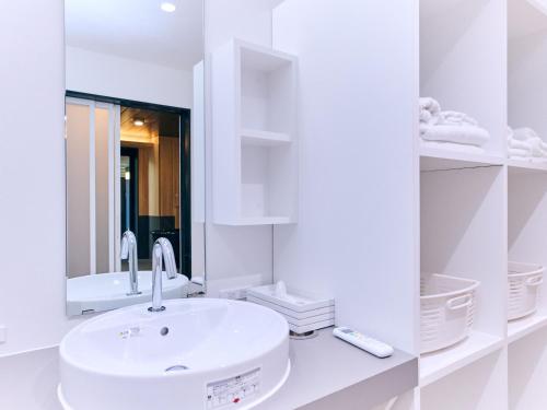 a white bathroom with a sink and a mirror at Amakusa Santacoming Hotel in Amakusa
