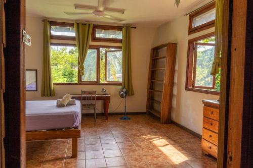 a bedroom with a bed and a desk and windows at Garden Rooms in Bocas del Toro