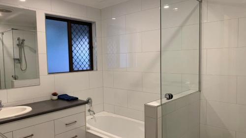 a white bathroom with a tub and a sink at Lowset pet friendly home, with room for a boat, Palm Ave, Bongaree in Bellara