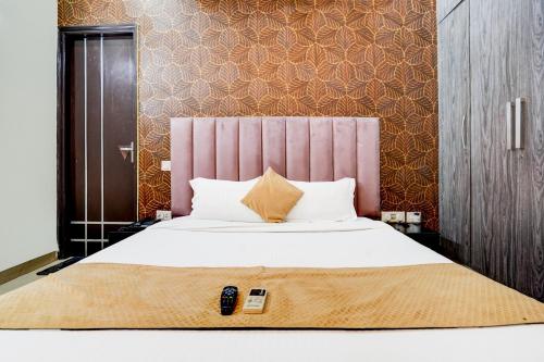 a bedroom with a large bed with two remote controls on it at FabExpress Next Home - Nr IMT Chowk Manesar in Gurgaon