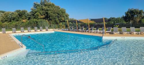 une grande piscine bleue avec des chaises et des chaises dans l'établissement LE COTTAGE DE LYXIE-Nature et sports, à Talmont-Saint-Hilaire