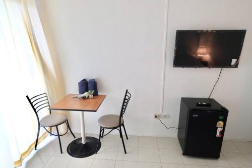 a room with a table and chairs and a tv on the wall at Airport View Apartment Cozy room near Airport in Samutprakarn