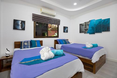 two beds in a room with blue and white at Villa Paradise Island in Rawai Beach