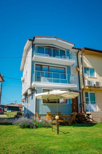 a building with an umbrella and a table and chairs at Summer Blue - Holiday House in Shabla