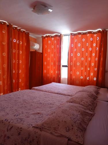 a bedroom with orange curtains and a bed at Orquídea's Hotel in Piura