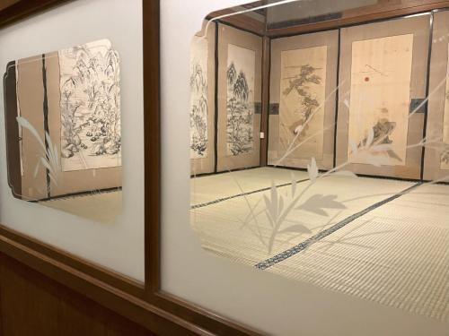 a display case in a room with drawings on the wall at 一日一組限定 古民家の宿 勝右衛門 吉野 in Oyodo