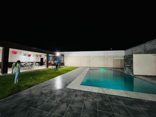 a woman standing next to a swimming pool at night at quinta la gaviota in Gómez Palacio