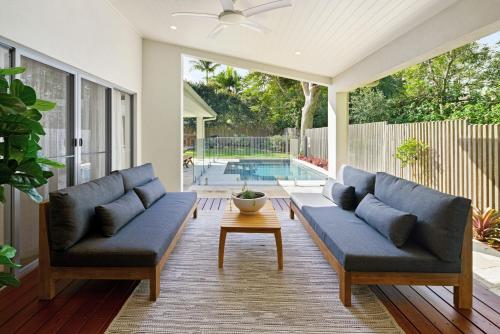 a patio with blue couches and a table and a pool at Home away from Home at Dicky Beach in Caloundra
