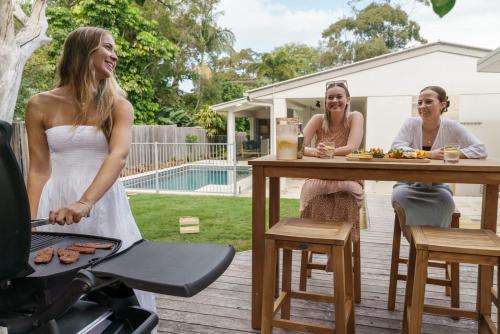 a bride is cooking on a grill with two women at Home away from Home at Dicky Beach in Caloundra