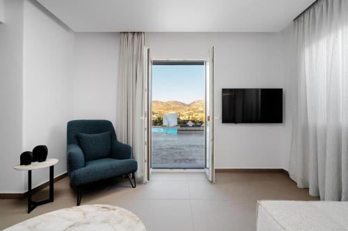 a living room with a blue chair and a television at Thalelion 3 bedroom Villas with private pool and Jacuzzi in Naxos Chora
