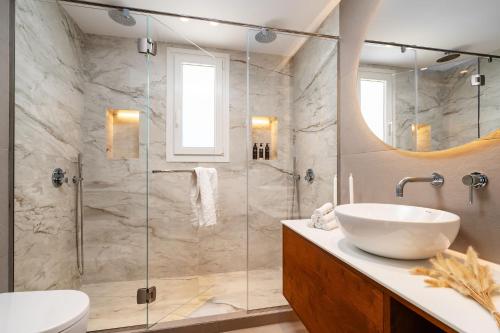 a bathroom with a sink and a glass shower at Thalelion 3 bedroom Villas with private pool and Jacuzzi in Naxos Chora