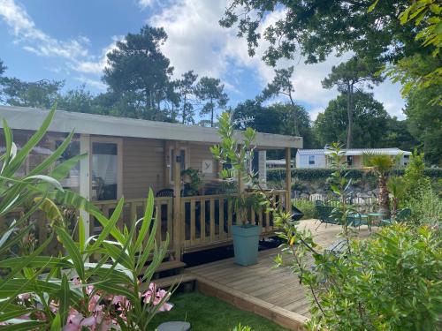 une petite maison avec une terrasse dans un jardin dans l'établissement Mobil home 3 chb tout confort, Espace Enfants - Claouey Cap Ferret, à Lège-Cap-Ferret
