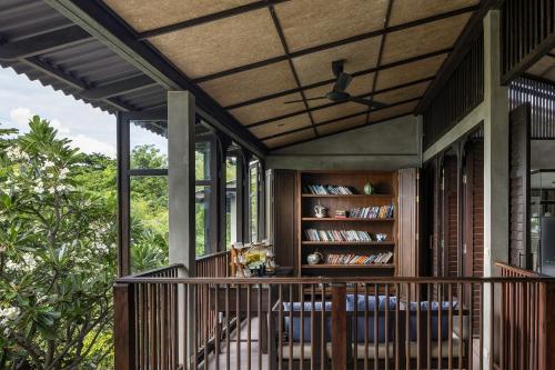 a screened in porch with chairs and a book shelf at Homm Chura Samui in Chaweng