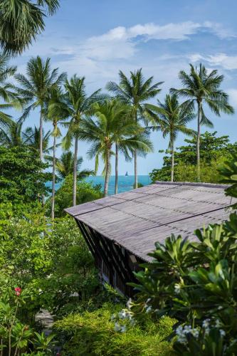 a building with palm trees in the background at Homm Chura Samui in Chaweng