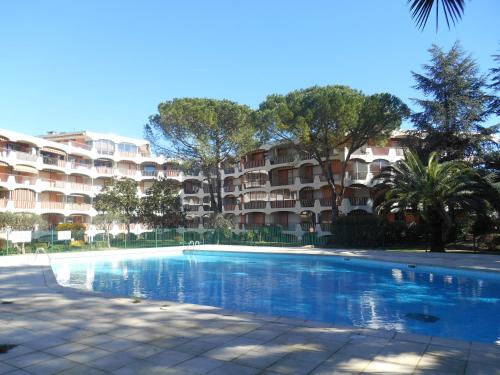 une piscine devant un grand immeuble d'appartements dans l'établissement Charmant 2 pièces proche de Cannes, à Mandelieu-la-Napoule