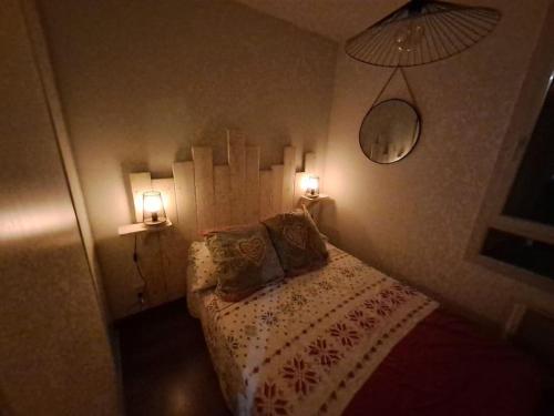 une chambre avec un lit avec deux lampes dessus dans l'établissement l été en montagne avec piscine 7 personnes, à Ax-les-Thermes