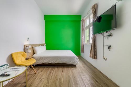 a room with a green wall and a bed and a desk at 5-1 Homestay in Kenting