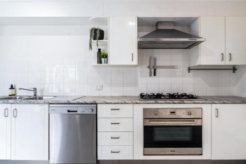 a kitchen with white cabinets and a stove top oven at Hidden Gem 200m to Mooloolaba Beach in Mooloolaba