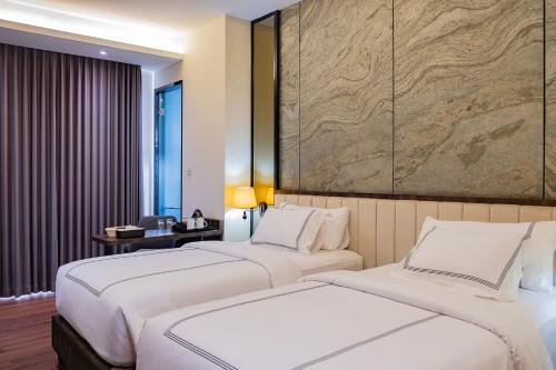 two beds in a hotel room with a large painting on the wall at BEST WORLD KINDAI HOTEL in Banjarmasin