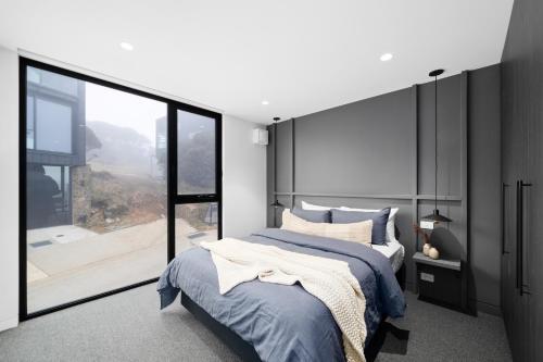a bedroom with a large bed and a large window at Luxury KH Chalet in Mount Hotham