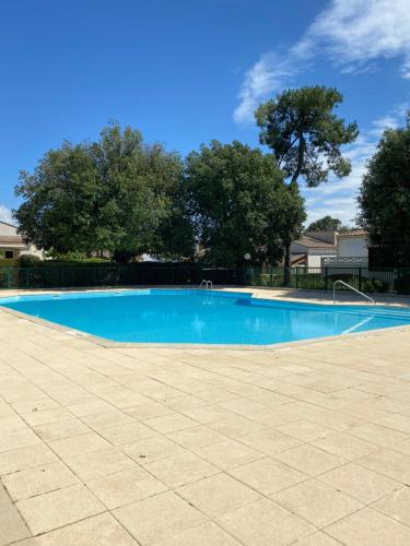 une grande piscine bleue avec des arbres en arrière-plan dans l'établissement Villa les hauts de St palais, à Saint-Palais-sur-Mer
