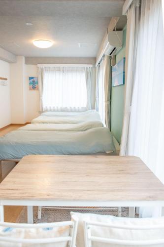 a bedroom with two beds and a table and a window at Upper Hotel Ishihara in Tokyo