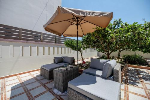 a patio with an umbrella and wicker chairs and an umbrella at Kira's Lovely Villa Massari in Haraki