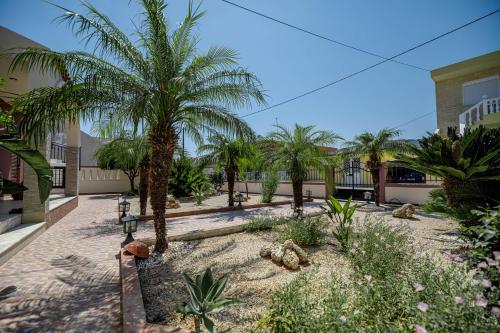 a courtyard with palm trees and a building at Kira's Lovely Villa Massari in Haraki