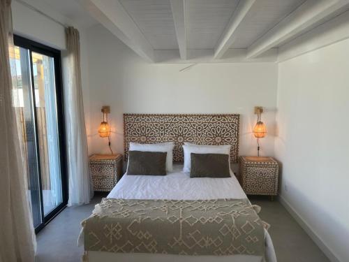 a bedroom with a bed and two lamps on two tables at Casa Zavial in Carrapateira
