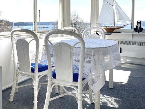 a white table with three chairs and a sailboat in a room at 4 star holiday home in UDDEVALLA in Uddevalla
