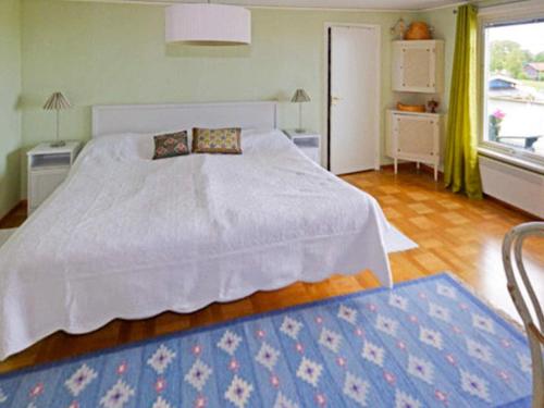 a bedroom with a white bed and a blue rug at 9 person holiday home in Skummeslövsstrand in Skummeslövsstrand