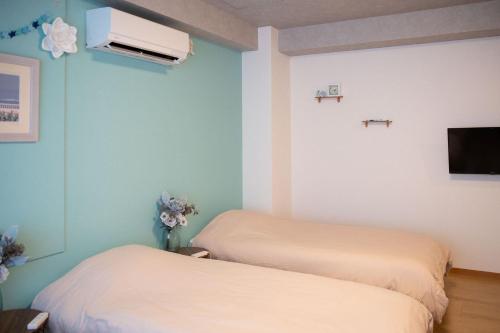 a room with two beds and a tv on the wall at Upper Hotel Ishihara in Tokyo