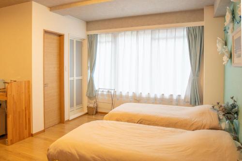 a bedroom with two beds and a window at Upper Hotel Ishihara in Tokyo