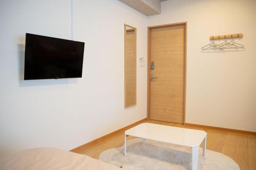 a living room with a tv and a white table at Upper Hotel Ishihara in Tokyo
