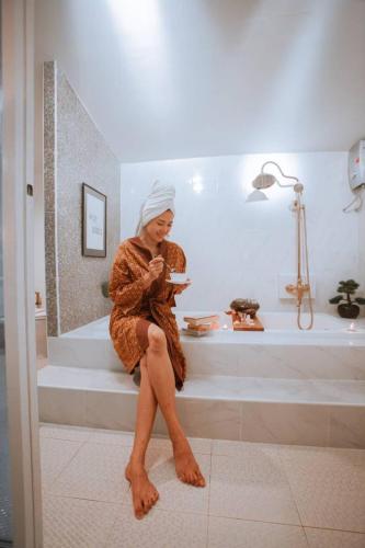 a woman sitting on the steps in a bathroom at The Antique Riverside Resort in Ban Pong